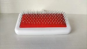 Detailed close-up of pet grooming brush head with red rubber base and protective white tips