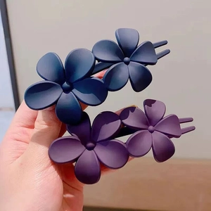 Detail view of matte flower hair clips in navy blue and purple shades for women