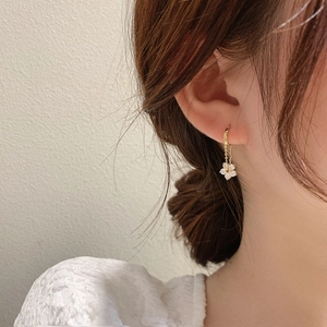 Elegant gold flower drop earrings featuring sparkling crystals on a female model