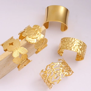 Close-up of gold stainless steel cuffs featuring butterfly, flower and hammered textures
