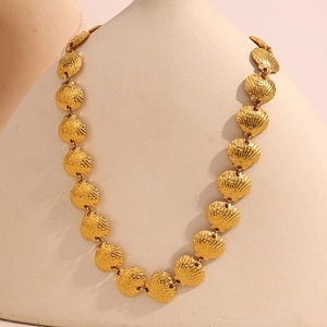 Détail du collier de coquillages plaqué or 18 carats sur un buste avec un éclairage doux