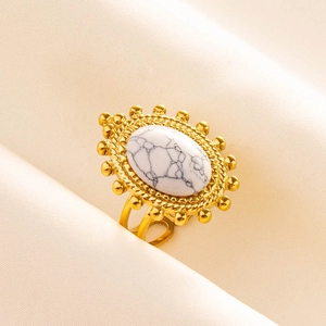 Vista macro di un anello vintage dorato con pietra di marmo bianco e dettagli di perle