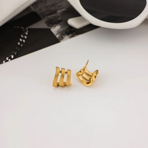Boucles d'oreilles chics à trois couches en acier inoxydable doré sur un bureau blanc