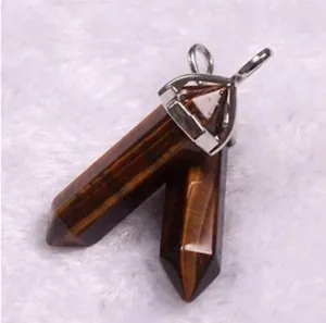 Macro shot of tiger eye stone hexagonal column pendants with silver metal clasps on white fur