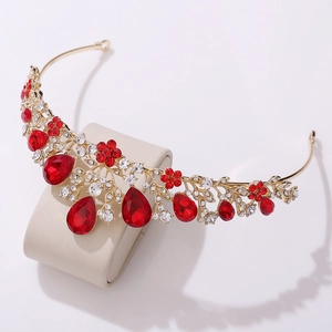 Close-up of golden bridal crown with red rhinestones and teardrop gemstone pendants