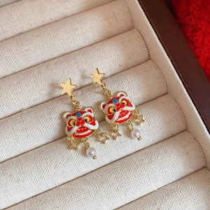 Detail of red lion dance earrings with enamel finish and pearl drop on jewelry box