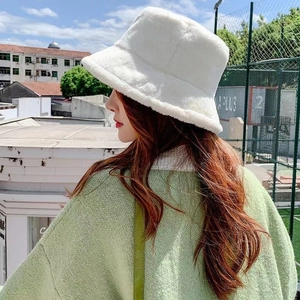 Outdoor side view of a woman wearing a thick white faux rabbit fur bucket hat