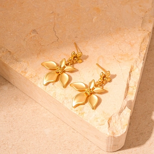 Elegant gold flower petal stud earrings with a matte metallic finish on natural stone background