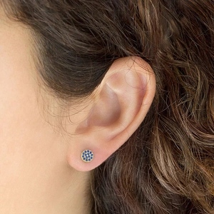Close-up of gold stainless steel stud earrings with blue pave crystals on earlobe