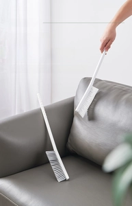 Long-handle radiator cleaning brush on a sofa for household dust removal