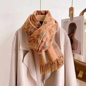 Close-up of floral paisley patterns and tassel details on a warm ethnic style shawl scarf