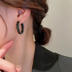 Gros plan de créoles noires avec pierres de zircone rectangulaires sur un modèle