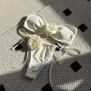 Detail of cream bikini set with large 3D fabric rose decorations on a textured rug