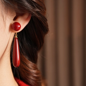 Detailed view of dark red resin teardrop earrings featuring a glossy polished finish