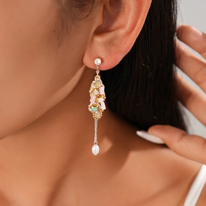 Gros plan de boucles d'oreilles à pompons avec cristaux colorés et perle blanche sur modèle