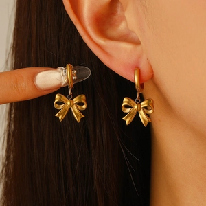 Elegant gold bow-shaped stainless steel huggie earrings for women on model