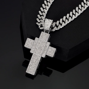 Macro shot of silver-tone iced out cross pendant with cubic zirconia on Cuban link chain