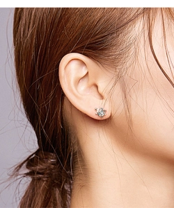 Close-up of a silver sea turtle stud earring with blue inlay worn by a female model