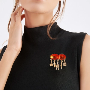 Halloween pumpkin brooch with golden charms on a black sleeveless turtleneck top