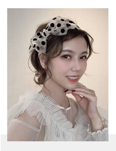 Close-up of model wearing an elegant beige polka dot bow headband with sheer mesh texture
