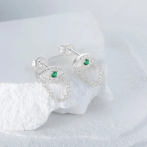 Detailed macro view of S925 silver Evil Eye stud earrings with green zircon and tassel