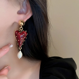 Détail de boucle d'oreille cœur vintage avec émail rouge et perle baroque