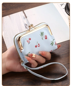 Detail of light blue cherry print wallet with gold clasp held against a cafe background
