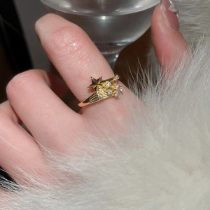 Detailed close-up of a gold-plated star ring with white zircons on a model's hand