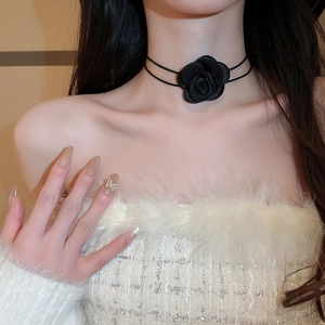 Close-up of handmade black fabric rose choker necklace on model with white furry top