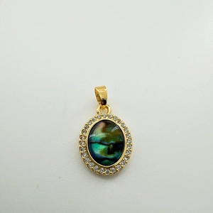 Detailed view of oval golden pendant with abalone shell inlay and sparkling crystals