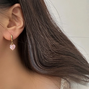 Elegant gold heart earrings with pink cubic zirconia crystal shown on a model