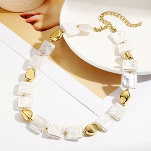 Detail of baroque pearl necklace with gold irregular beads and adjustable chain on porcelain