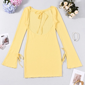 Détail de la robe courte en maille jaune avec dos nu lacé et poignets évasés à lanières