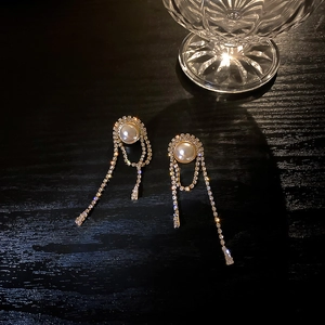 Close-up of elegant gold tassel earrings with round pearls and sparkling rhinestones