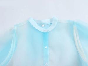 Dettaglio camicia in organza azzurra con stampa a palma, collo alla coreana e bottoni
