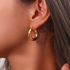 Close-up of a polished 18K gold-plated stainless steel hoop earring on a model ear