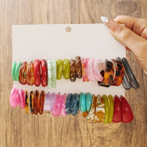 Détail de boucles d'oreilles créoles en acrylique coloré avec textures de résine variées