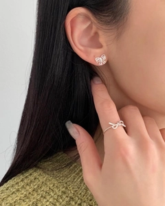 Close-up of model wearing 925 silver hollow bow earrings and matching knotted ring