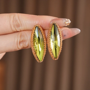 Close-up of olive green marquise crystal earrings with gold micro-pave detailing