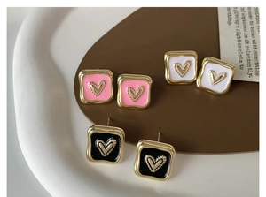 Dettaglio di orecchini a cuore in smalto rosa, bianco e nero con bordo placcato oro