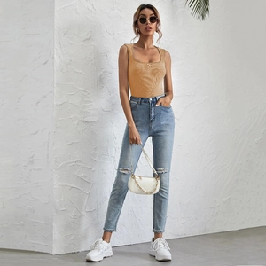 Close-up of ginger yellow U-neck slim fit bodysuit paired with light blue distressed jeans
