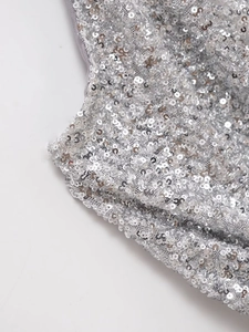 Gros plan de paillettes argentées scintillantes sur tulle gris avec finition métallique