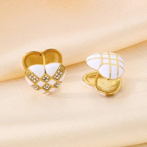 Macro shot of checkered heart earrings with white enamel and rhinestones on silk