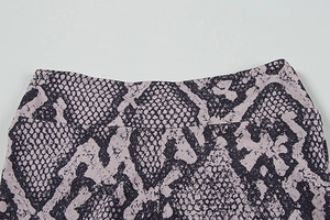 Detailed view of high-waist yoga pants featuring purple snake print and durable stitching