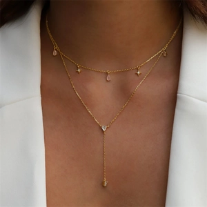 Detail of layered gold S925 silver necklace with star and pink teardrop pendants