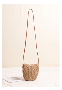 Close-up of hand-woven straw bucket bag showing natural texture and leather strap