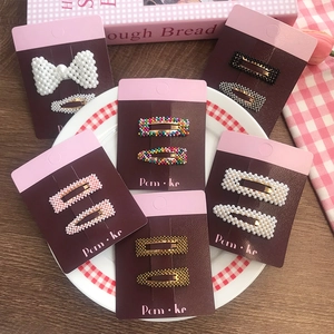 Close-up of cute pearl and rhinestone hair clips set displayed on branded cardboards