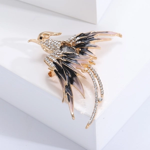Macro shot of gold phoenix brooch with black and pink enamel wings and sparkling rhinestones