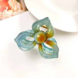Detailed top view of a hollow plumeria hair claw clip with blue and amber resin marbling