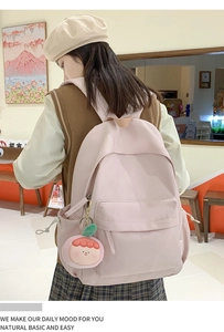 Detailed close-up of a pink nylon backpack with a cute peach plush charm on back